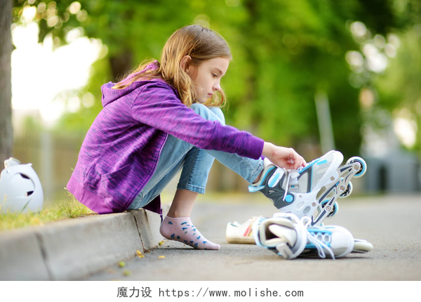 漂亮的小女孩在公园穿旱冰鞋漂亮的小女孩在公园的夏日里学习溜冰。儿童佩戴安全头盔享受轮滑骑在户外.